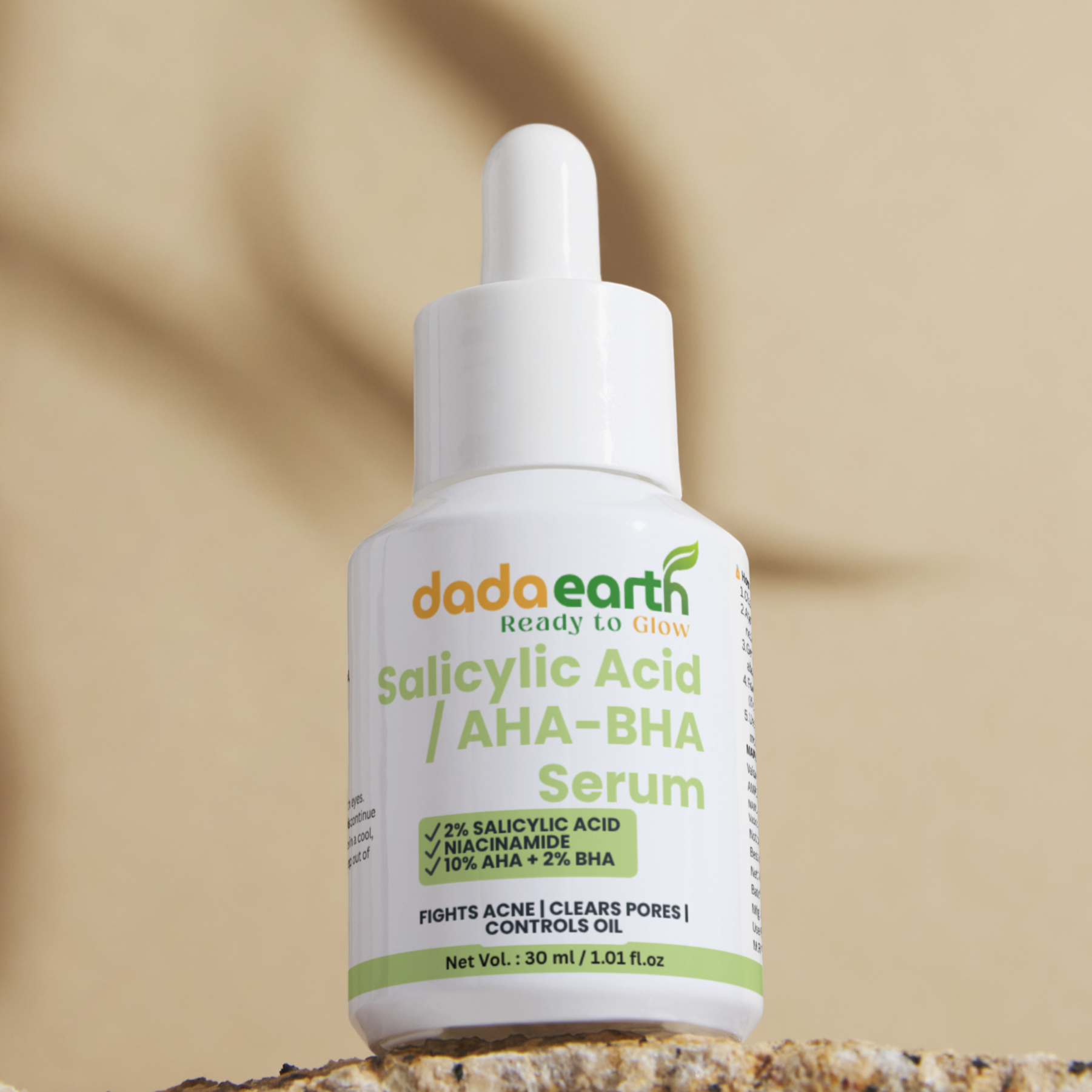 Dropper bottle of Dada Earth skincare product on a stone surface with a beige background